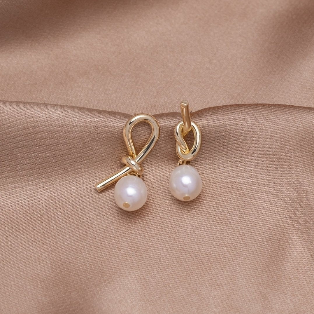 Knotted Gold & Freshwater Pearl Earrings, pair of gold knot earrings with pearl drops on beige satin
