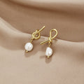 Knotted Gold & Freshwater Pearl Earrings, a pair of earrings lying on draped satin, pearl drops visible