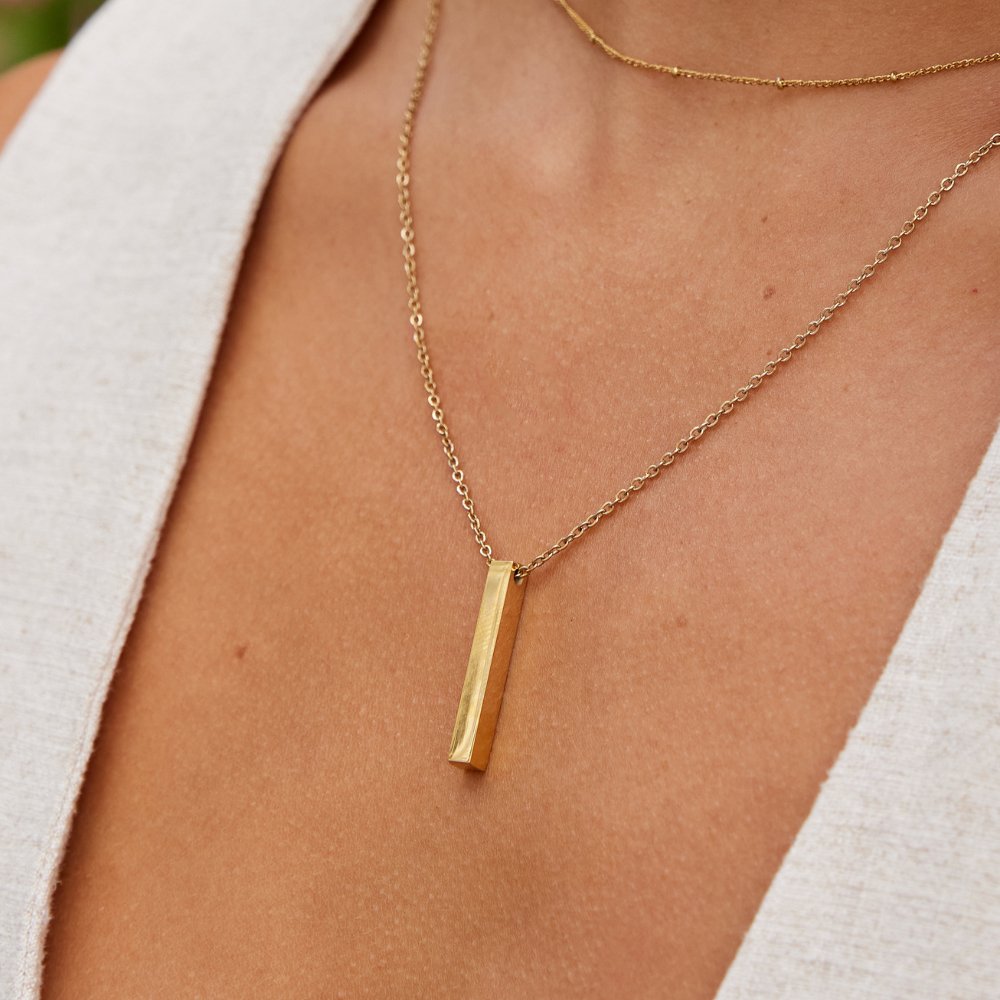 Lala Gold Bar Necklace, worn on a neck over a white linen top, gold bar pendant
