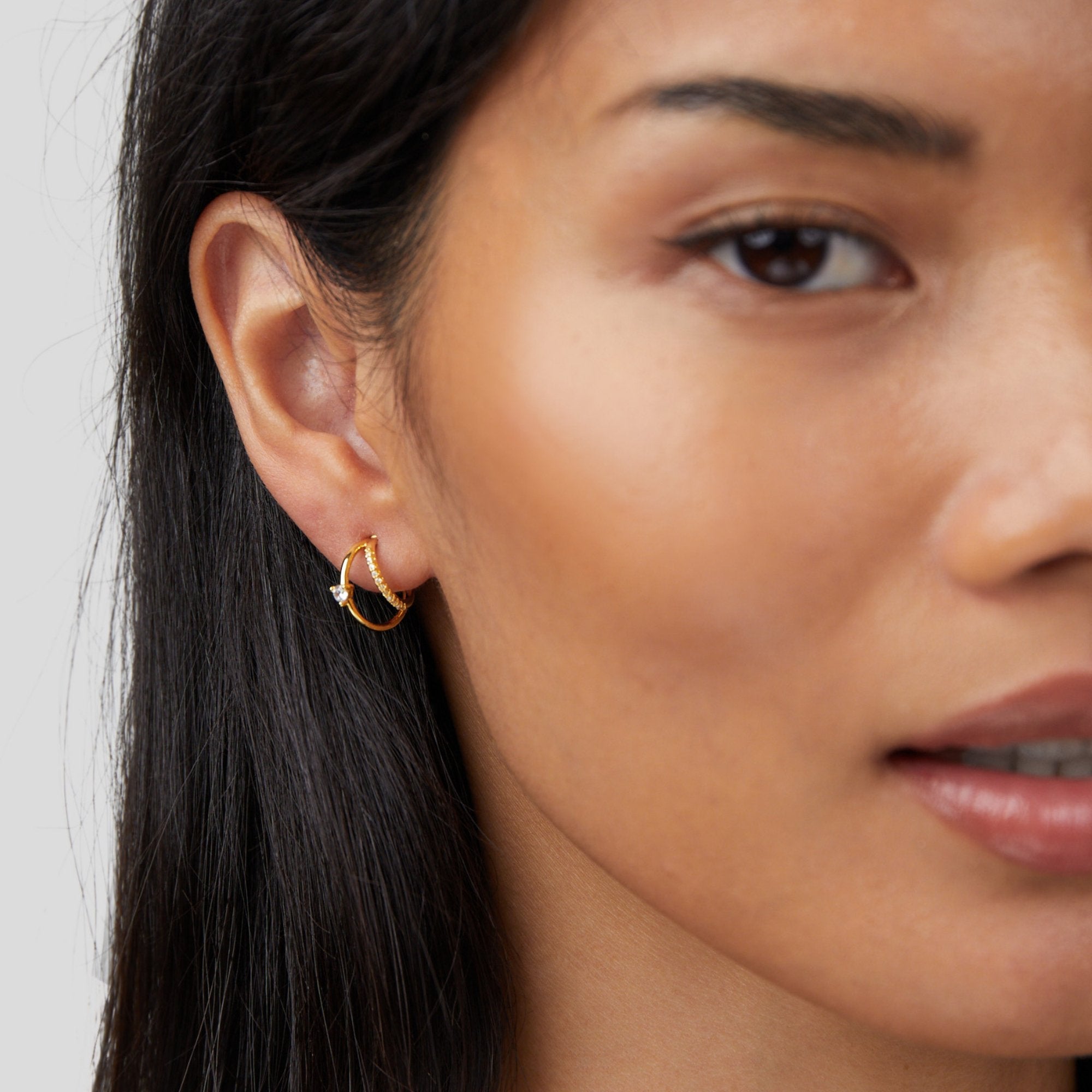 Layered Crystal Gold Hoop Earrings, worn on an ear, close-up with gold hoops and a small stone
