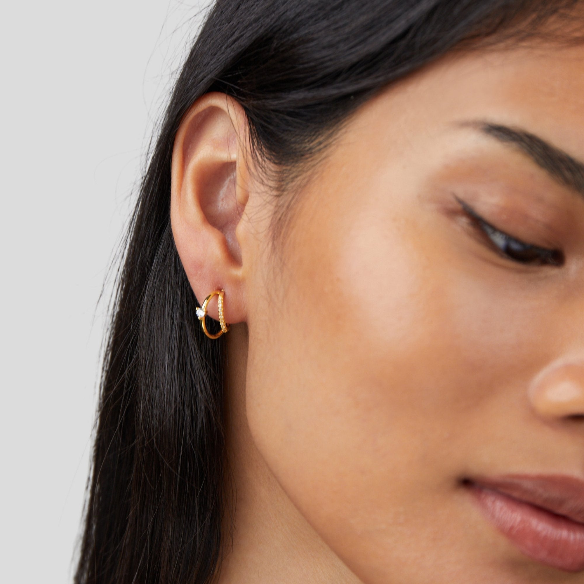 Layered Crystal Gold Hoop Earrings, worn on an ear, close-up with gold hoops and small white stones