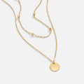 Layered Disc Necklace, laid flat on white, two gold chains with a round disc pendant