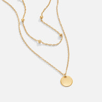 Layered Disc Necklace, laid flat on white, two gold chains with a round disc pendant