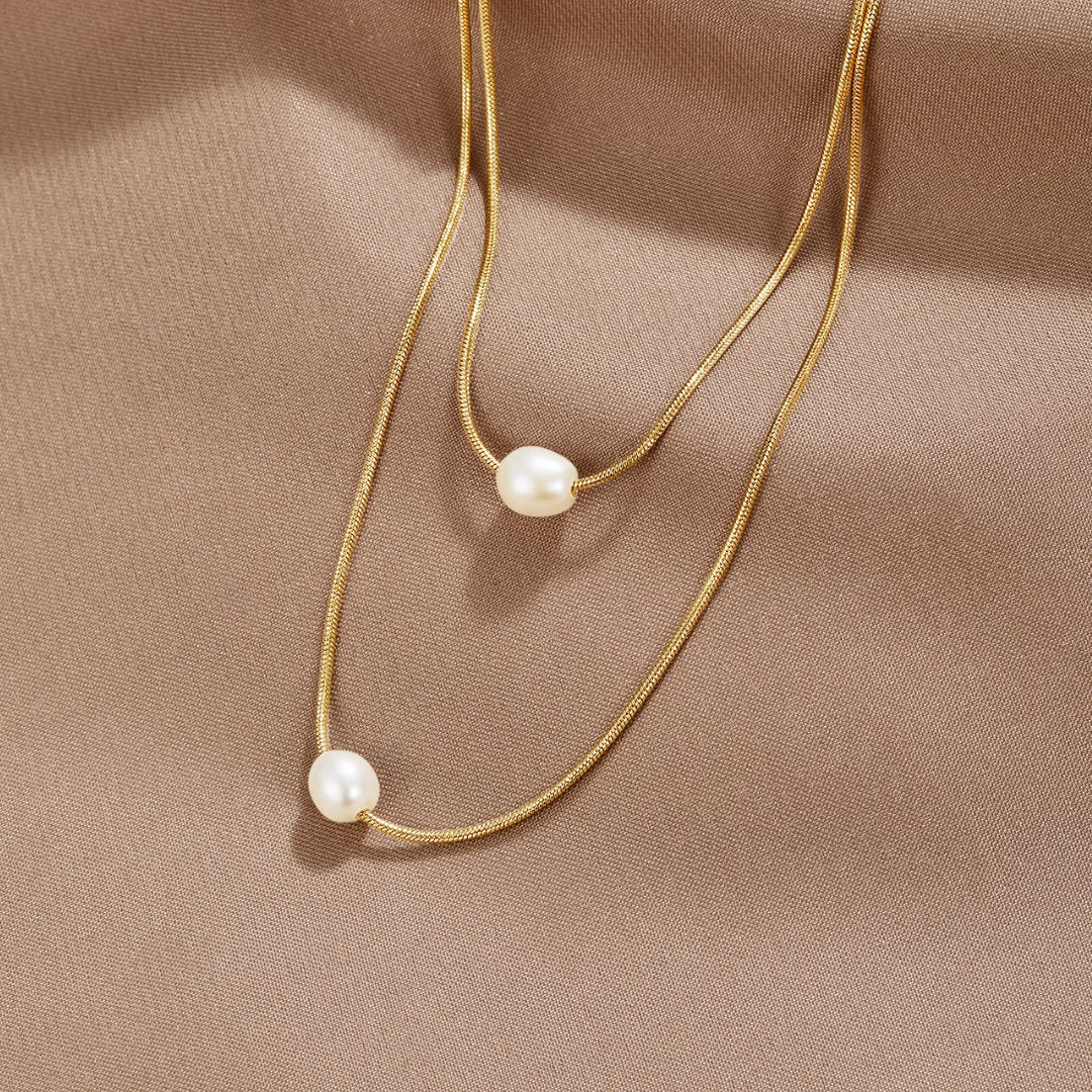 Layered Freshwater Pearl Necklace, two gold chains laid on satin, each with one pearl