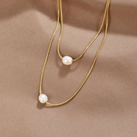 Layered Freshwater Pearl Necklace, two gold chains laid on satin, each with one pearl