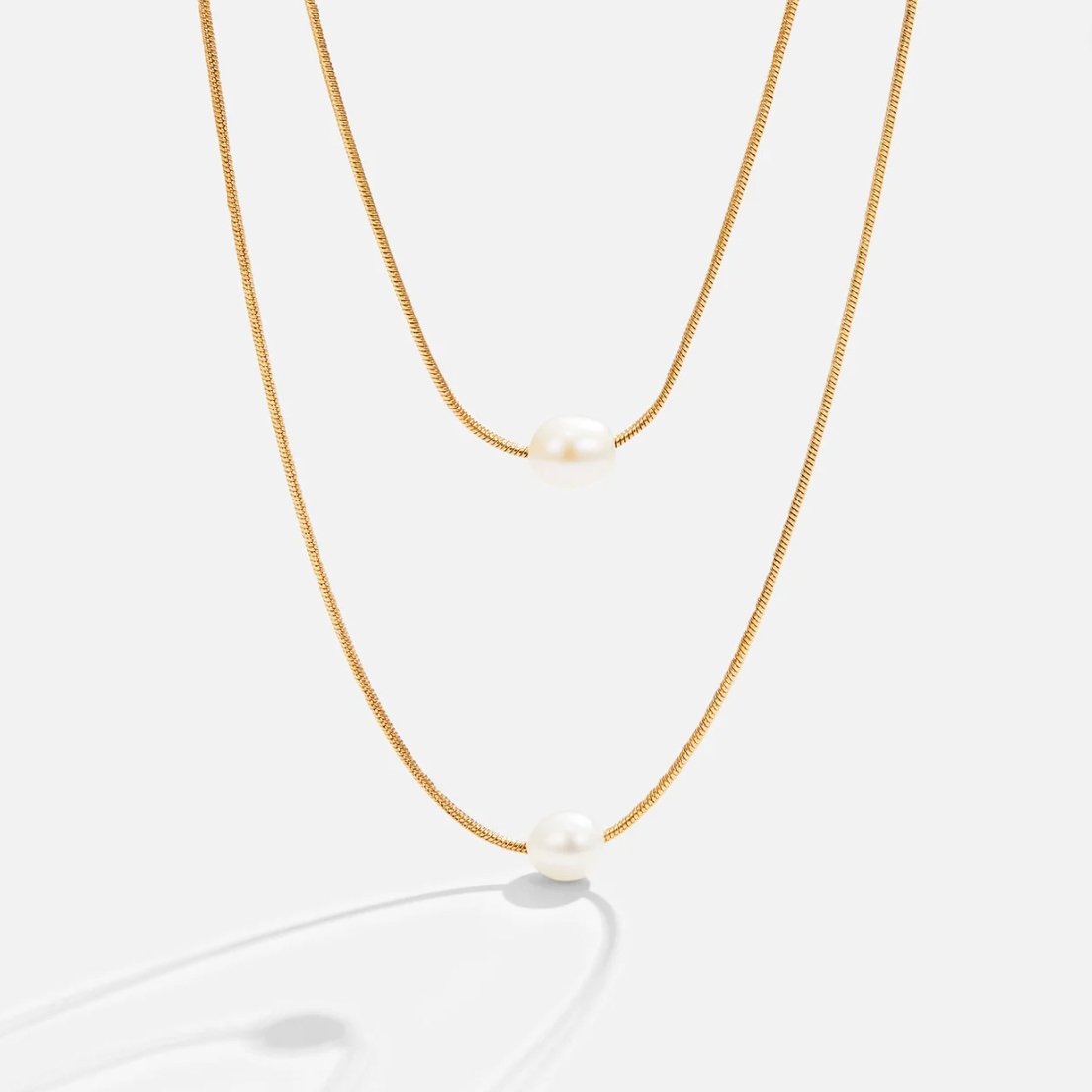 Layered Freshwater Pearl Necklace, two gold chains layered with a pearl on each, on white