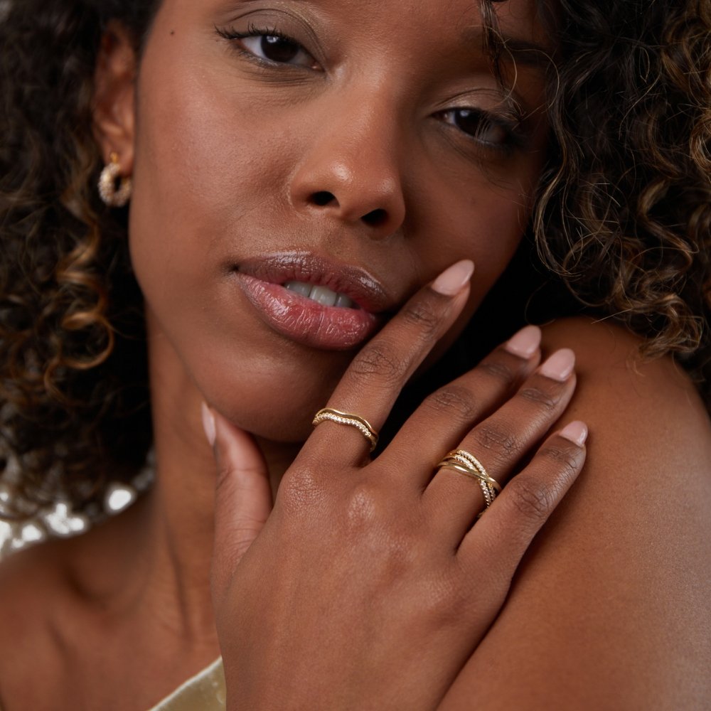 Layered Juni Gold & Crystal Ring, worn on a hand touching a model's cheek, gold rings with pavé