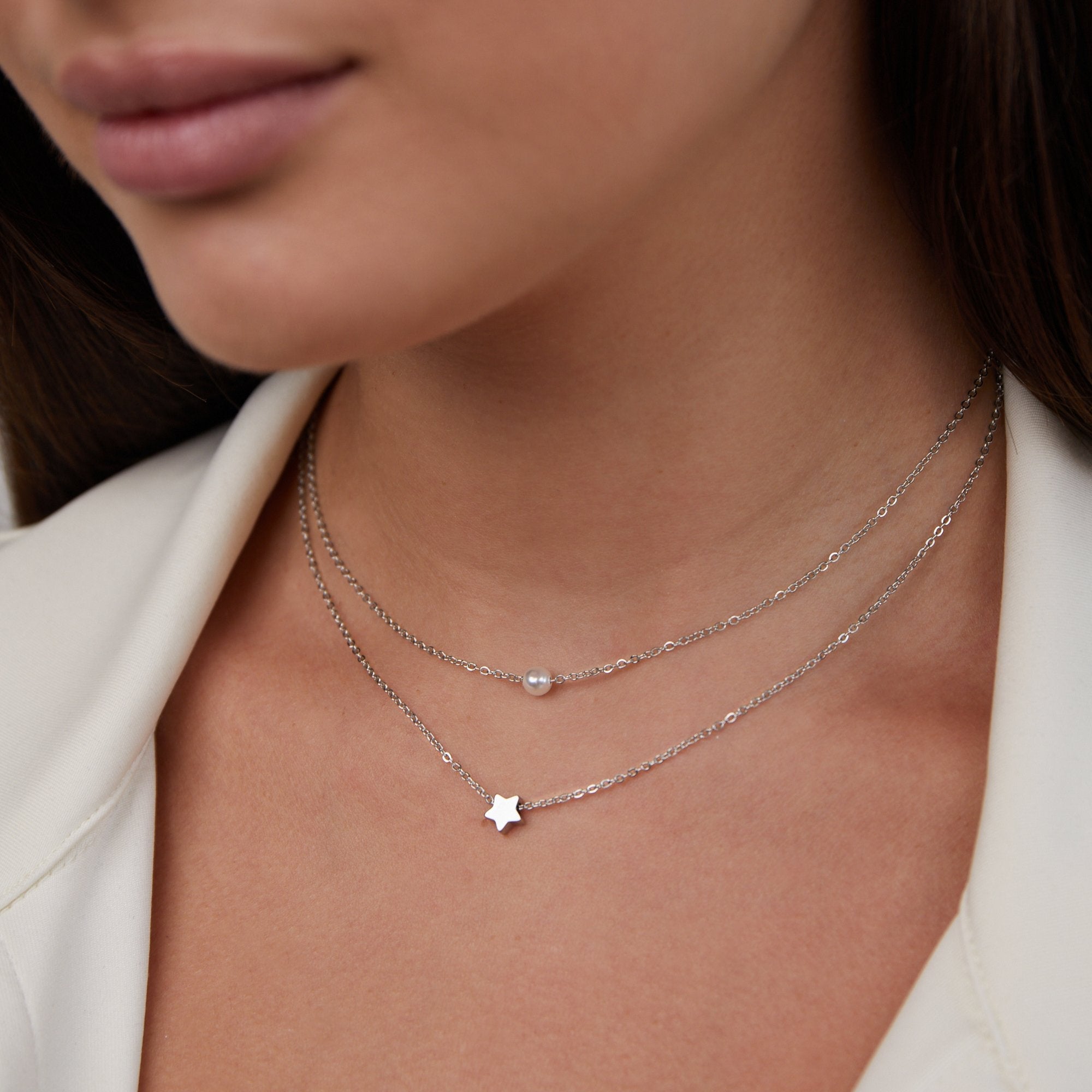 Layered Silver Star & Pearl Necklace, worn on a neck with a white jacket, close-up of the chains