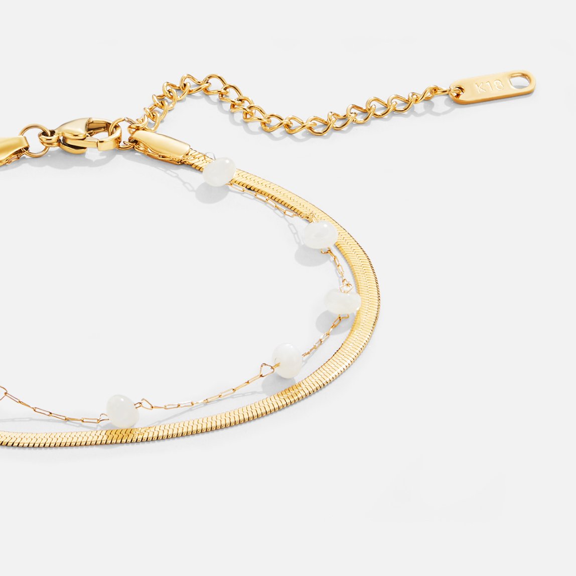 Layered Snake Chain Gold Anklet, close-up of a gold chain with white beads and extender tag