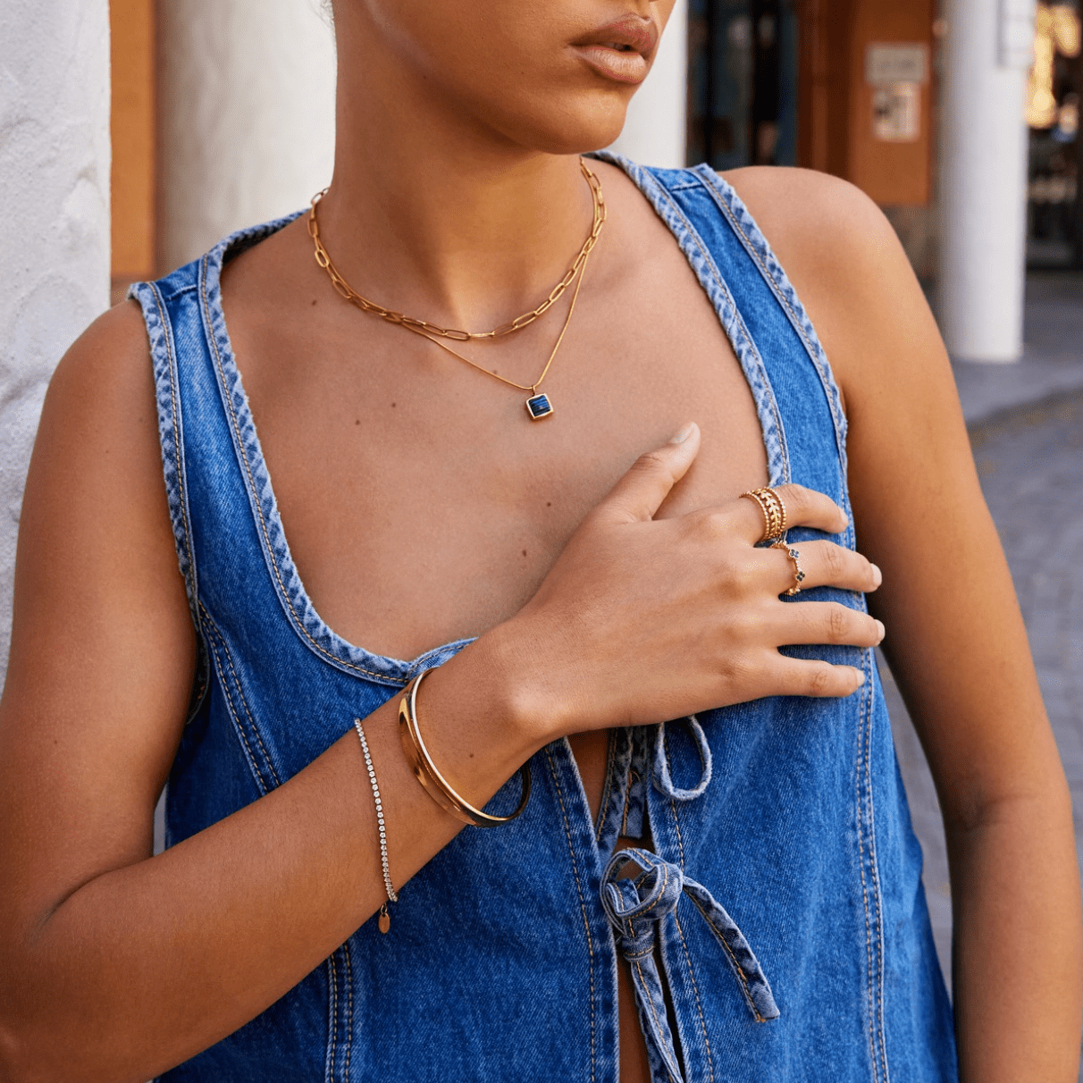 Leyla 18K Gold Bangle, worn on a wrist with a thin chain bracelet and rings