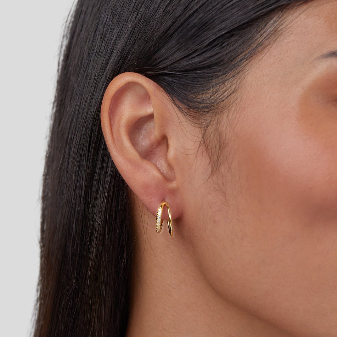 Leyla Crystal Double Hoop Earrings, worn on an ear, close-up of gold double hoops