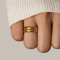 Lia Layered Gold Ring, worn on a finger below a cream knit sleeve, polished gold band