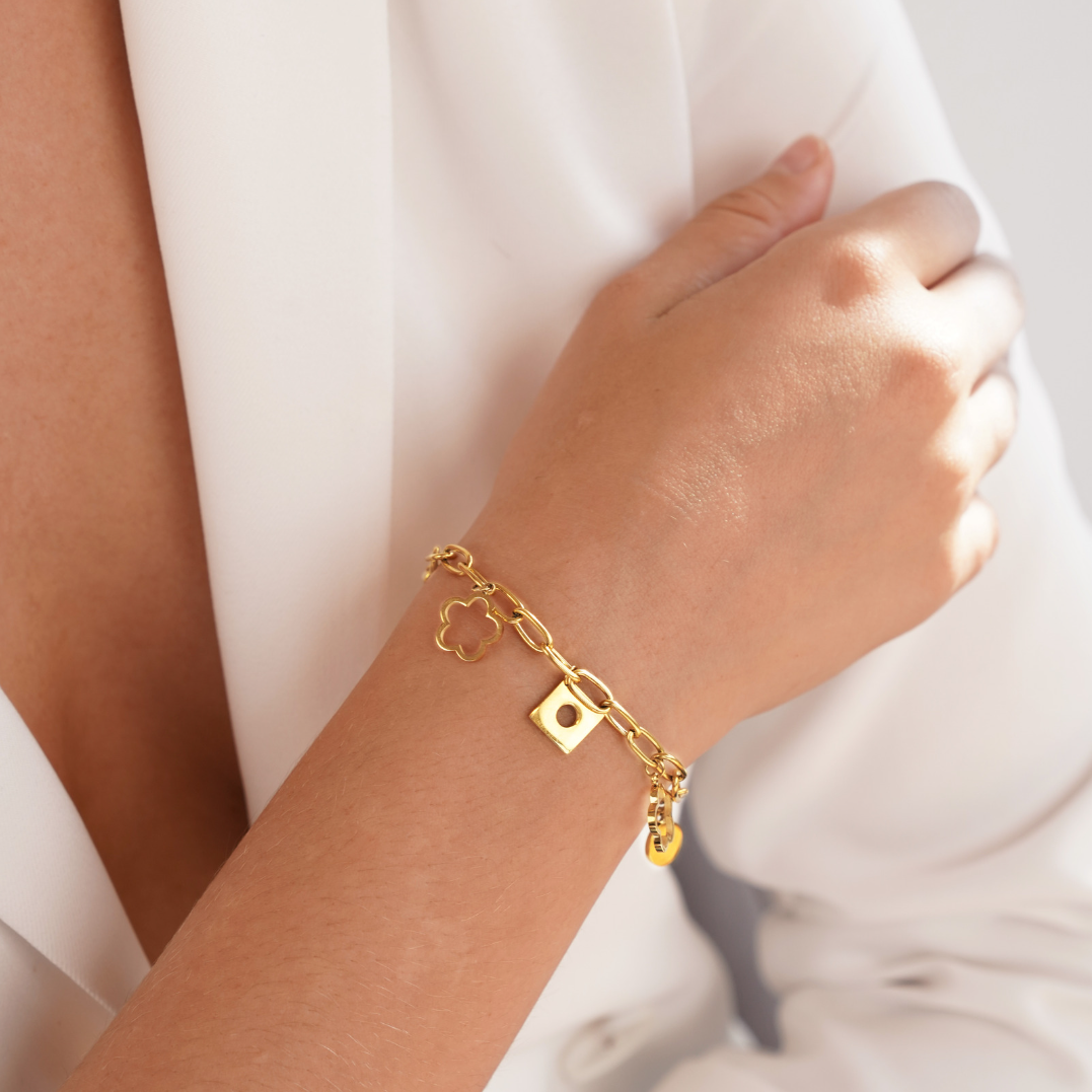 Lucky Daisy Charm Bracelet, worn on a wrist with a white blouse, gold chain and charms