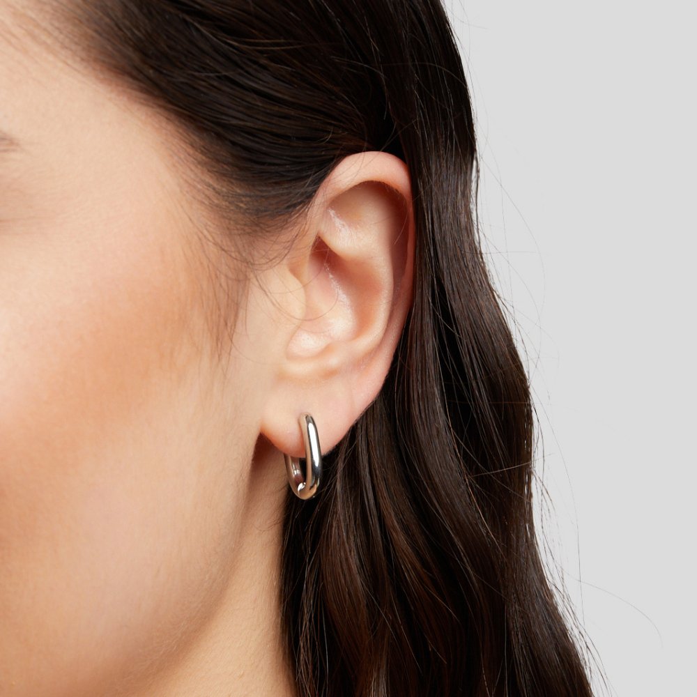 Madison Silver Hoop Earrings, worn in an ear, close-up of a polished silver hoop