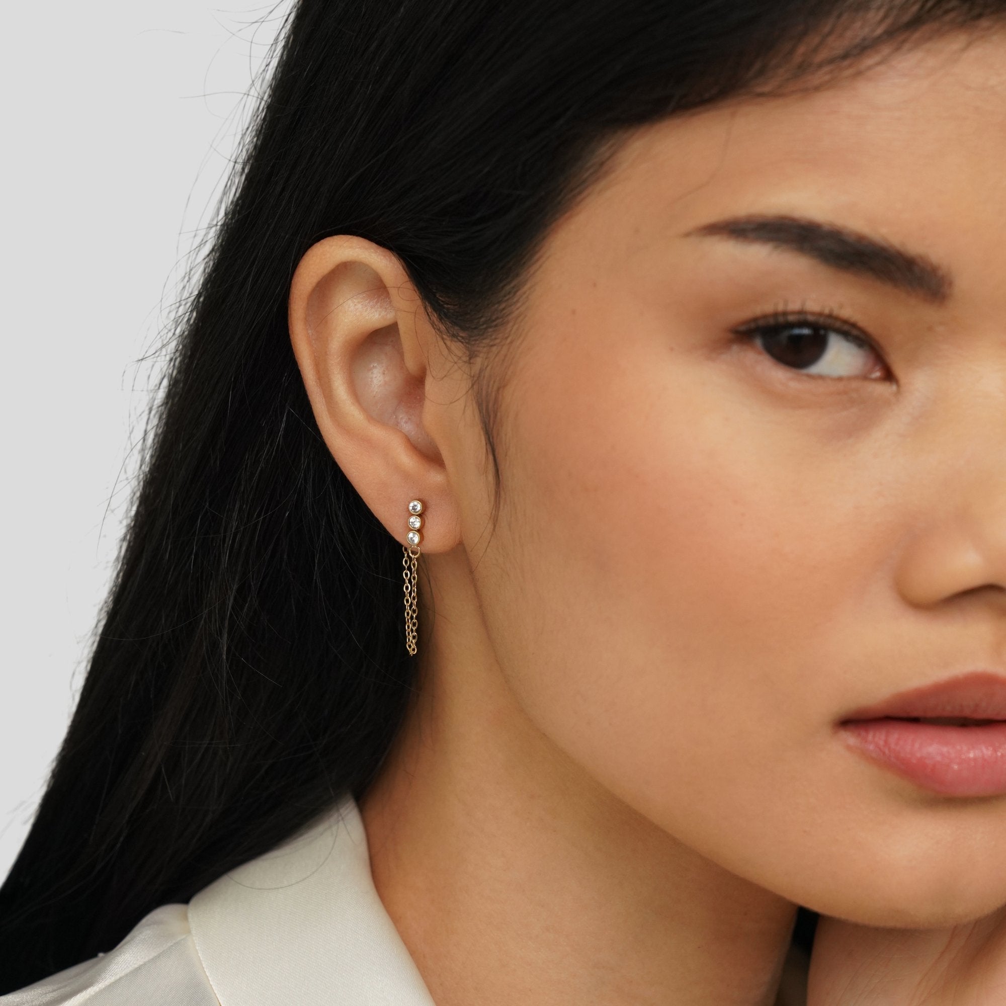 Mara Crystal Chain Earrings, worn on an ear with three small stones and a fine gold chain