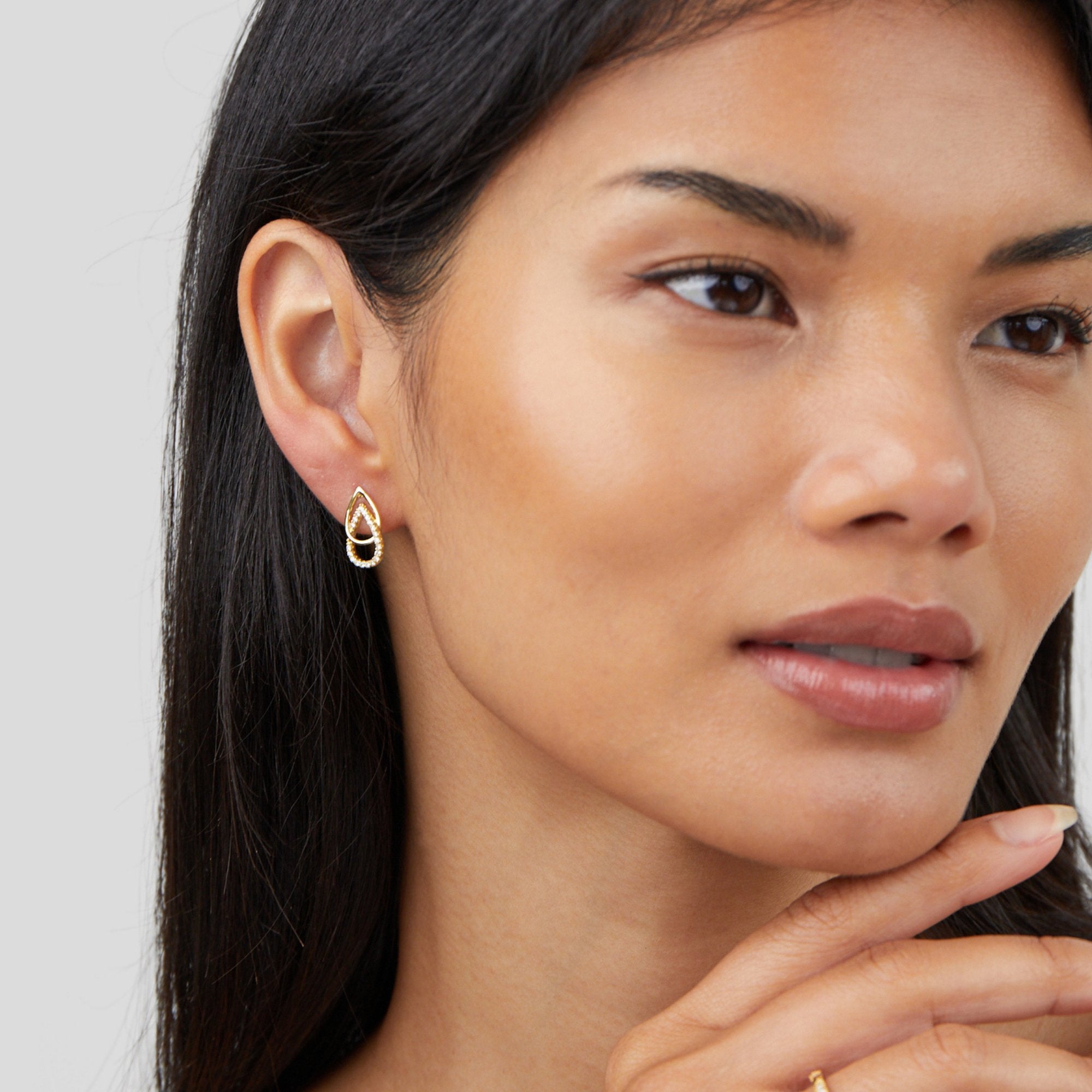 Mara Teardrop Link Earrings, worn on an ear by a model with long dark hair, gold teardrop drop