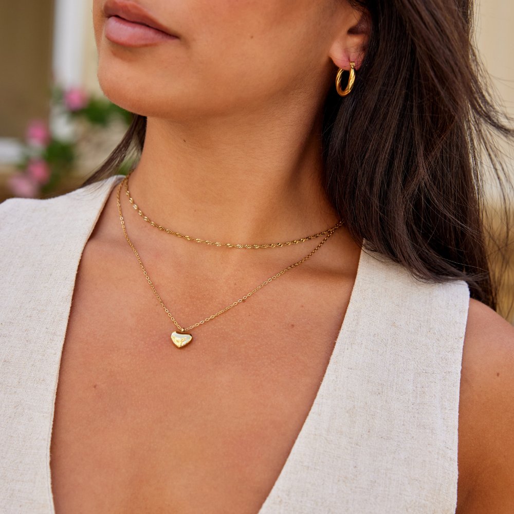 Marina Love Gold Necklace, worn on a model with a gold hoop earring and white top