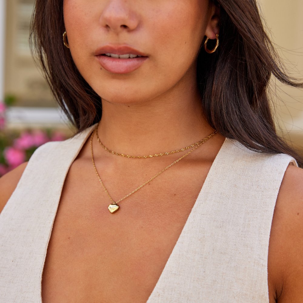 Marina Love Gold Necklace, worn on a neck with two layered gold chains and a heart pendant