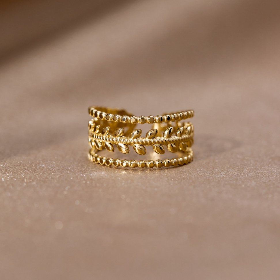 Marissa Layered Gold Leaf Ring, standing upright on a soft beige fabric, gold leaf band