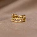 Marissa Layered Gold Leaf Ring, standing upright on a soft beige fabric, gold leaf band