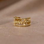Marissa Layered Gold Leaf Ring, standing upright on a soft beige fabric, gold leaf band