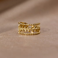 Marissa Layered Gold Leaf Ring, standing upright on a soft beige fabric, gold leaf band