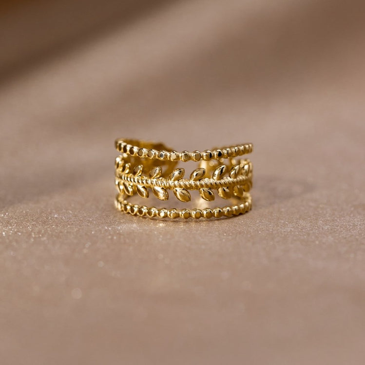 Marissa Layered Gold Leaf Ring, standing upright on a soft beige fabric, gold leaf band