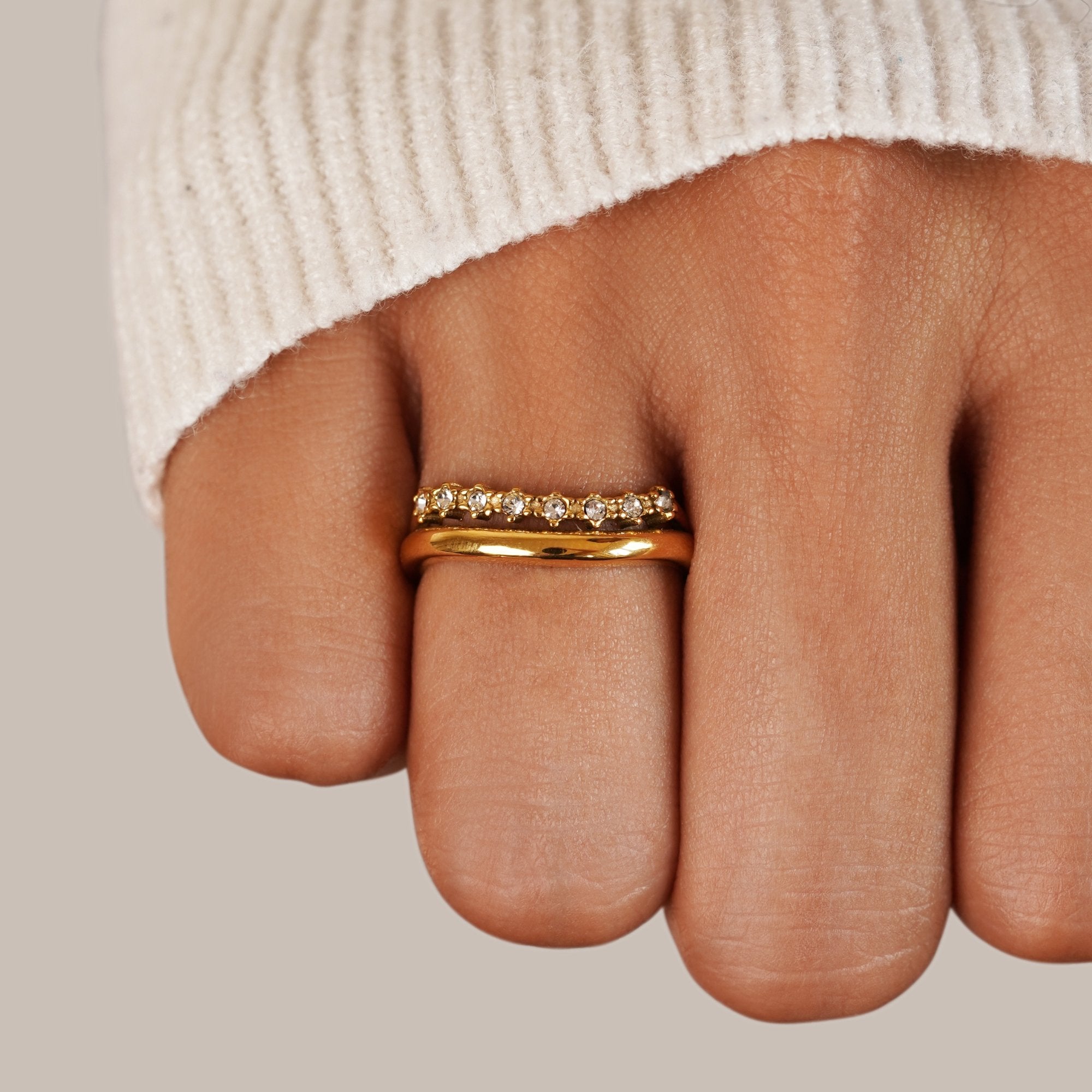 Marissa White Crystal Layered Ring, worn on a finger with a cream knit sleeve, close-up, gold