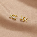 Midnight Magic Studs, pair of gold star studs on a beige fabric, one with small clear stones