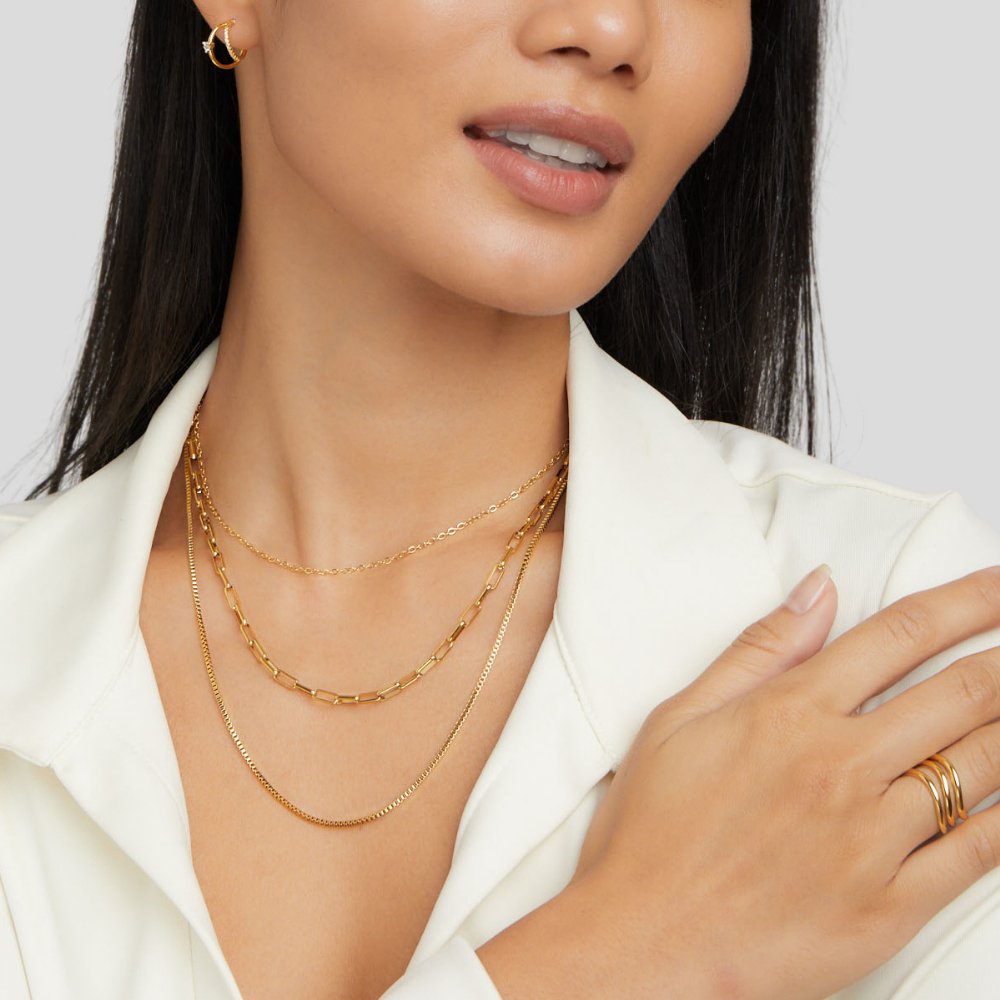 Miela Layered Chain Necklace, worn on a model in a white jacket, three gold chains layered