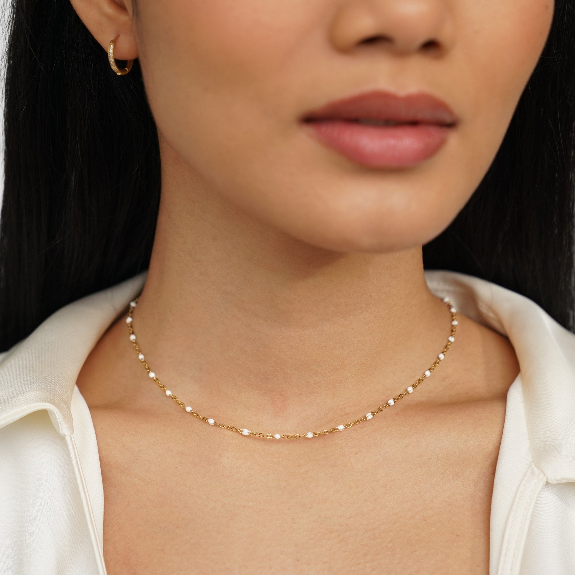 Mila White Bead Necklace, worn on a neck with a white open-collar top, gold chain with white beads