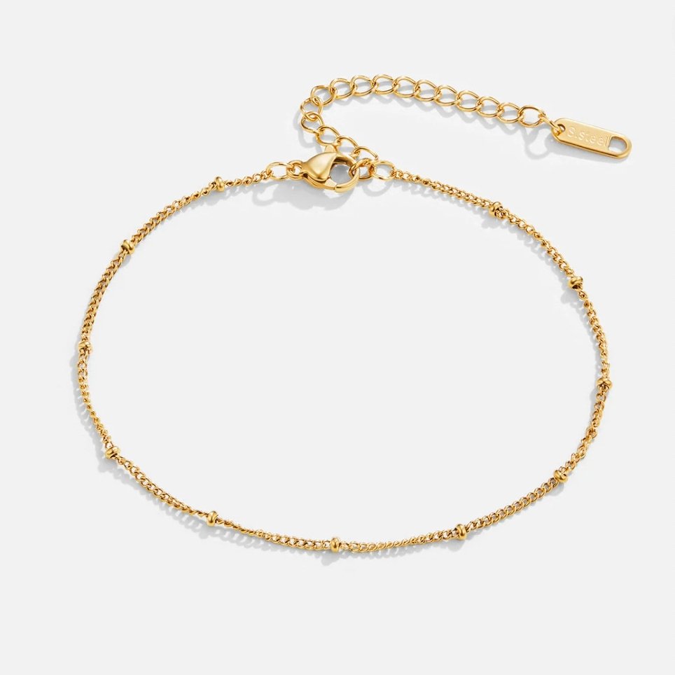 Mira Beaded Gold Anklet, laid flat on a light grey background, thin gold chain with small beads