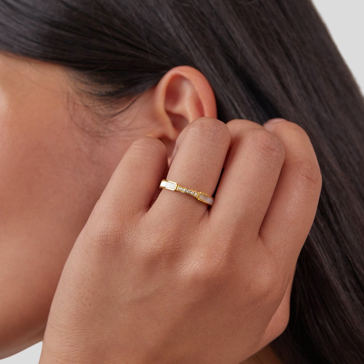 Mother Of Pearl & Crystal Ring, worn on a hand near an ear, gold band with pearl and crystal