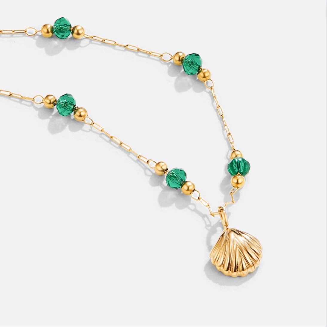 Nerissa Gold Shell & Green Bead Necklace, gold necklace laid flat on white, shell pendant with
