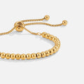 Niloya Beaded Gold Bracelet, close-up of gold beaded bracelet with sliding bolo adjuster on white