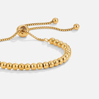 Niloya Beaded Gold Bracelet, close-up of gold beaded bracelet with sliding bolo adjuster on white