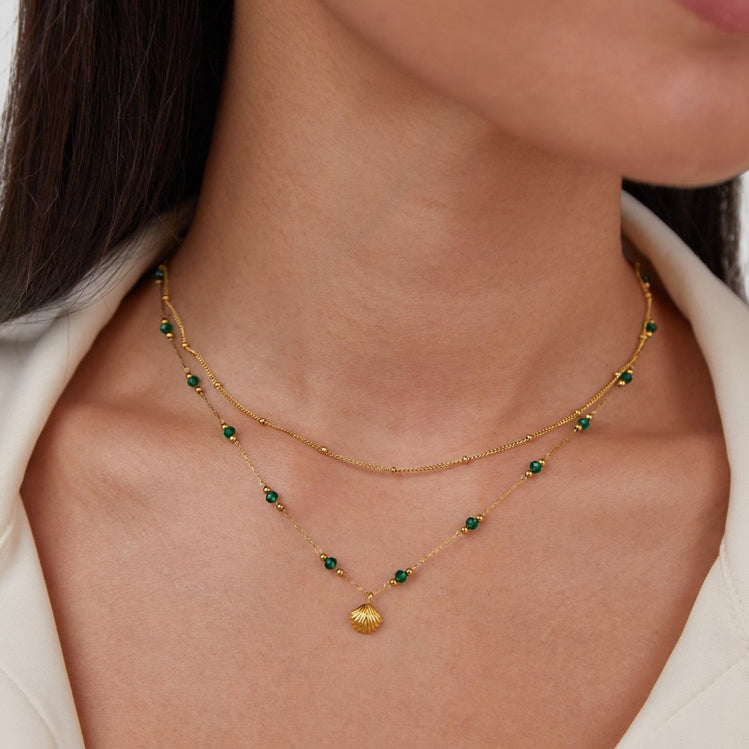 Niyah Bead Gold Chain Necklace, worn on a neck with two layered gold chains and green beads