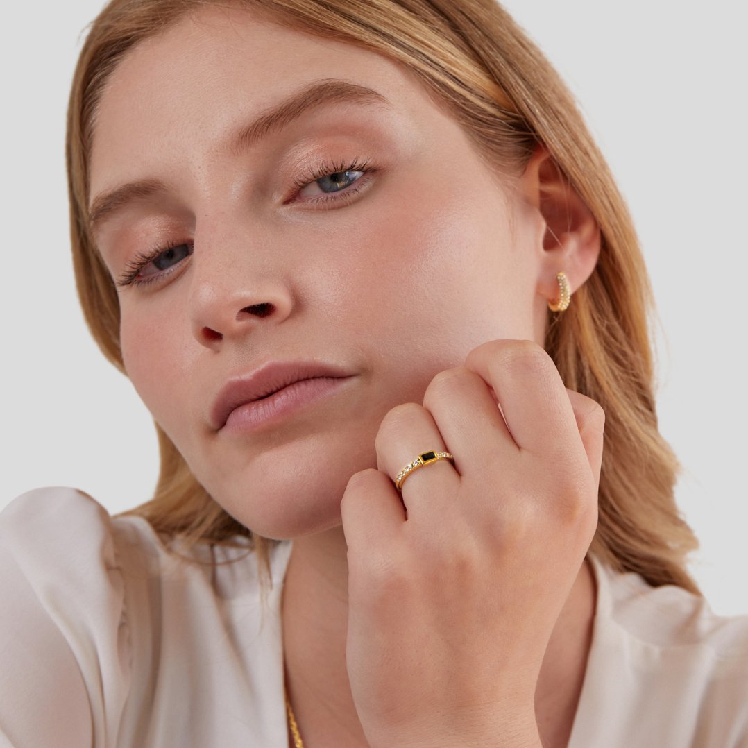 Onyx Black Crystal Ring, worn on a hand near the cheek, with a gold hoop earring