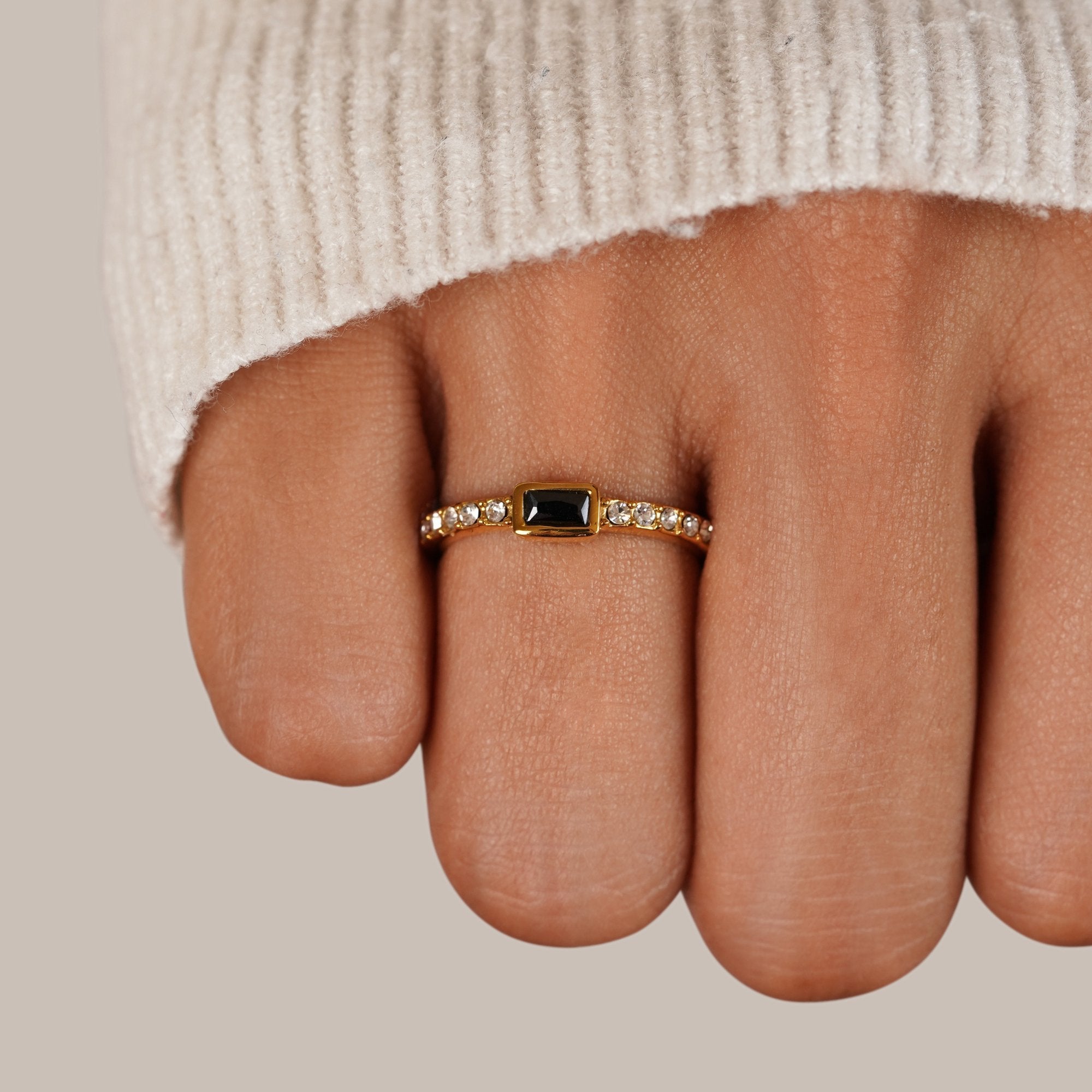 Onyx Black Crystal Ring, worn on a finger in a cream knit sleeve, black stone centred