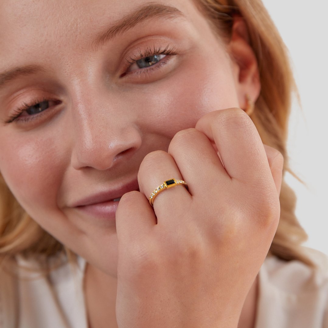 Onyx Black Crystal Ring, worn on a hand by a smiling woman, gold band with black stone