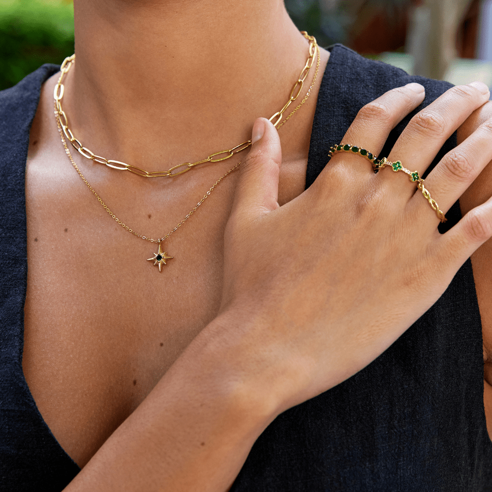 Paperclip Gold Necklace, worn on a neck with a star pendant and gold rings on a hand