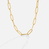 Paperclip Gold Necklace, gold elongated oval link chain laid in a curve on white background