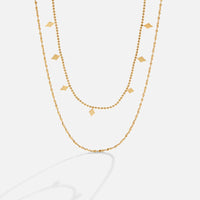 Phoenix Layered Necklace, two gold layered chains, one beaded with diamond-shaped charms, on white