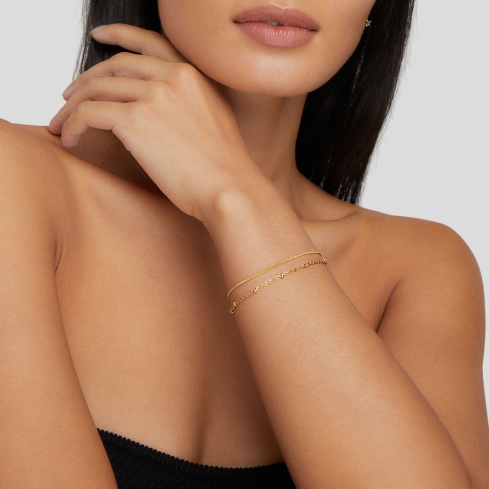 Pia Gold Layered Bracelet, worn on a wrist with a hand resting near the neck