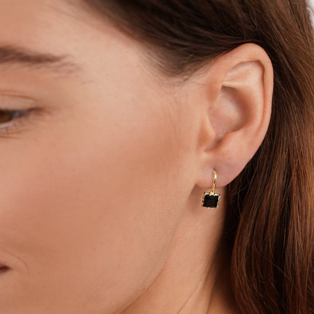 Piper Black Crystal Drop Earrings, worn on an ear, close-up with a square black stone and gold hoop