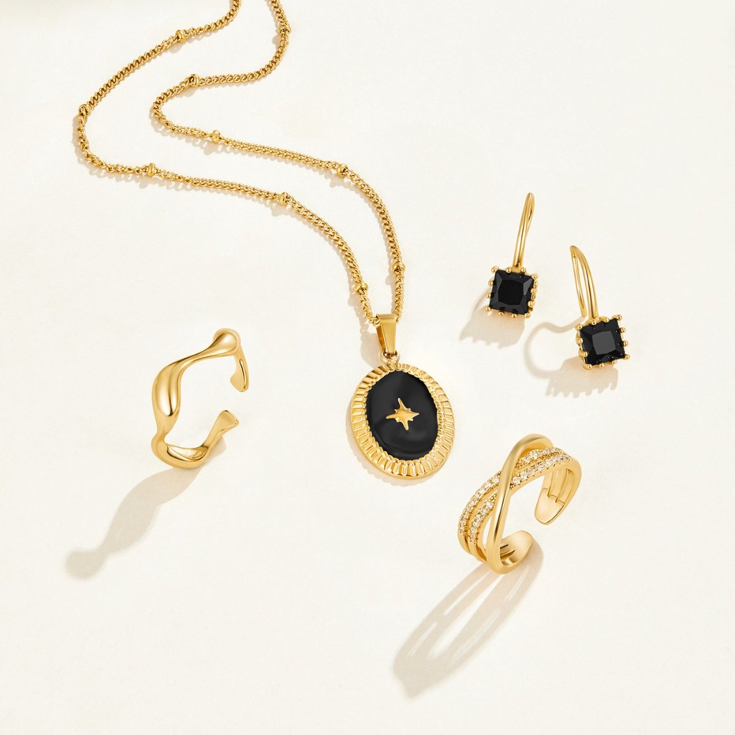 Piper Black Crystal Drop Earrings, flat-lay of necklace, earrings and two rings on cream background