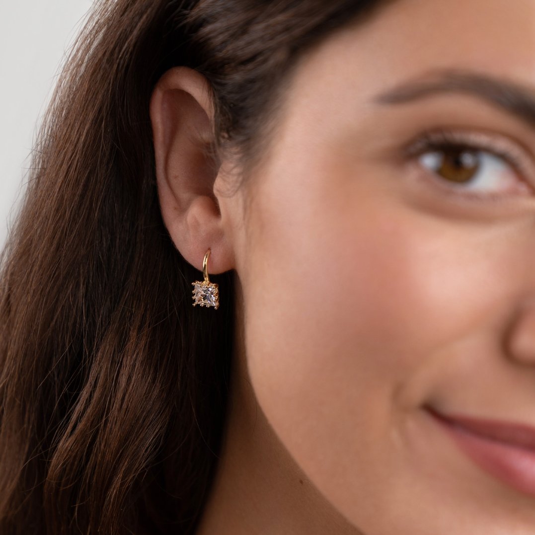 Piper Crystal Drop Earrings, worn on an ear, gold hoop with a square clear crystal drop