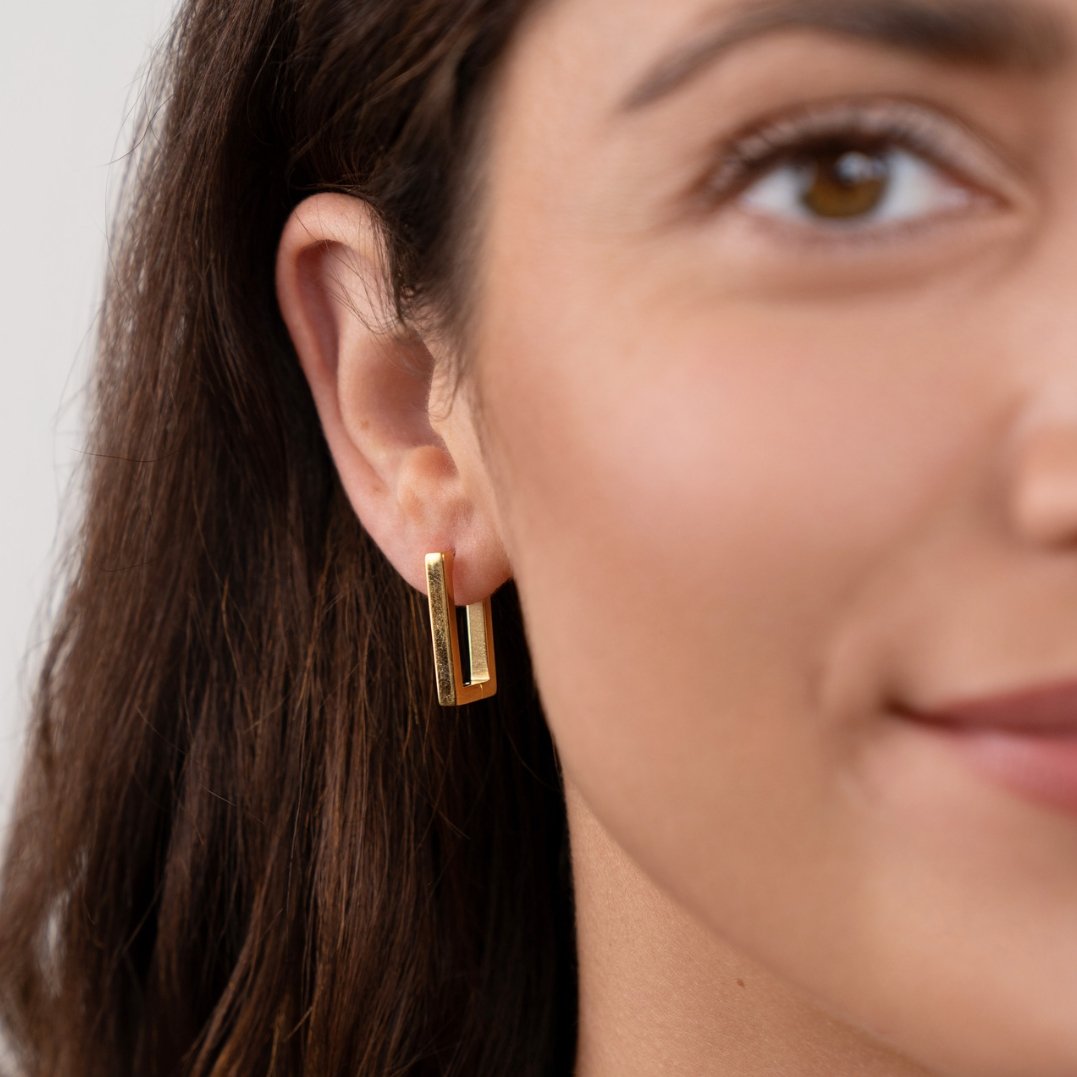 Gold Rectangle Hoop Earrings, worn on an ear by a woman with long brown hair