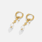 Rini Pearl Tassel Earrings, pair of gold hoop earrings with pearl drops, laid flat on white