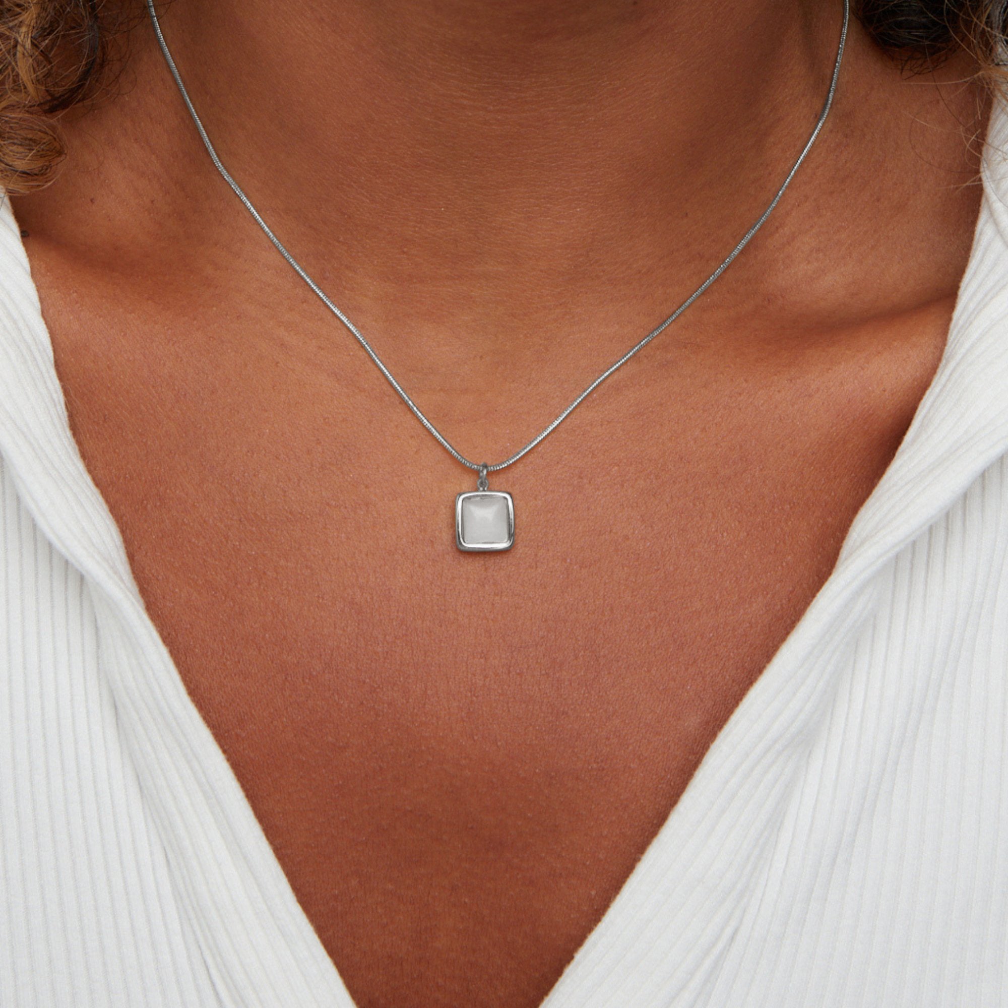 Riva Moonstone Pendant Necklace, worn at the neck over a white ribbed top, close crop